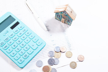 calculator and coins with house on white background