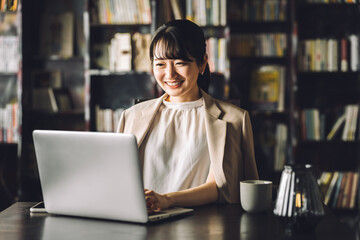 Young Asian businesswoman working on laptop in her study, library
