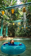 Little girl inside the giant float running through under bucket water in a water park in Malaysia.