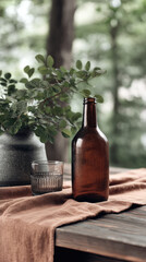Brown glass bottle and glass with leafy vase on rustic table