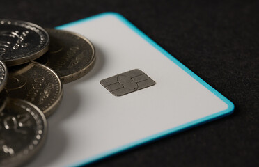 Close up of credit card chip and silver coins on black