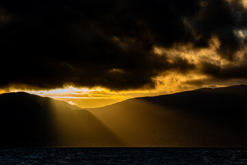 Sunrise over the Carneddau Mountains beneath dark, dramatic cloud cover