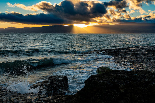 Sunrise light breaking through layered cloud over the Carneddau Mountains across the Menai Straits