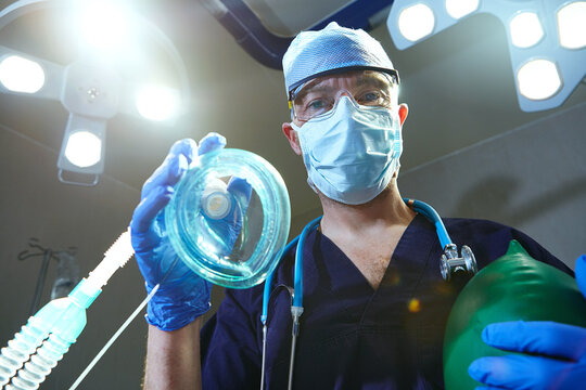 Low angle, portrait or surgeon in hospital with oxygen mask, breathing or anesthesia support in medical operation. Healthcare, POV or man with equipment, patient safety or sedation for surgery