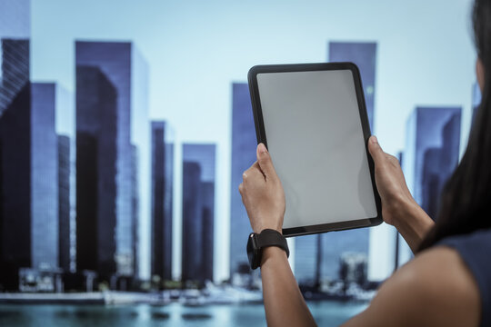 Businesswoman using digital tablet in modern city skyline environment, representing smart urban technology, mobile computing, business innovation, remote work, future smart city transformation. - Powered by Adobe
