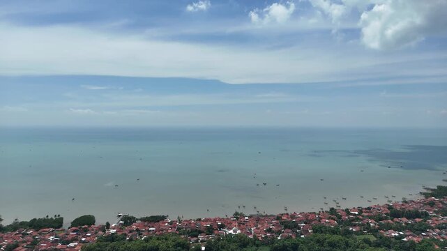 Aerial View of Tropical Coastal Village with Red Roofs and Blue Sea