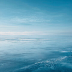Fototapeta premium A serene icy blue landscape with a smooth glass-like surface reflecting the sky. The scene evokes a winter aesthetic with cool tones and an arctic vibe.