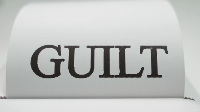 The large word GUILT appears on white paper, close-up