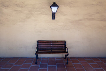 Wooden Bench and Wall Lantern Against Stucco Wall in Spanish Mission Architecture.