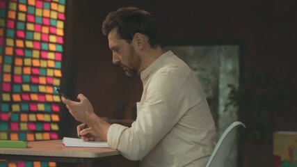 Artist jotting ideas diligently, Individual intensely concentrating while writing and drawing in studio