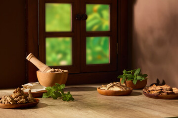 Rustic still life of dried herbs, roots, and natural ingredients arranged on wooden table near a window. Warm sunlight, traditional herbal atmosphere. Design product on blank surface © Tuan  Nguyen 