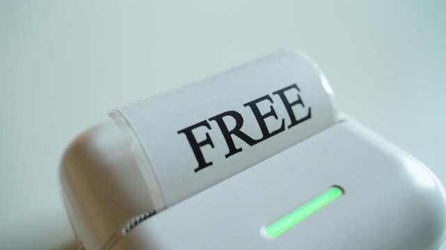 Mini printer prints the word FREE on white self-adhesive paper, close-up