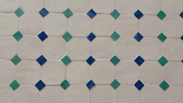 Close-up view of traditional Moroccan tiles. The intricate geometric pattern showcases vibrant blue and green diamonds set against a textured off-white background, visually appealing backdrop.