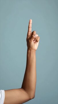 Arm and Hand Pointing Upward with Index Finger Extended on a Solid Background, Concept Idea or Attention Getter