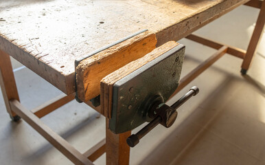 A workbench with a wooden top and a heavy-duty metal vise