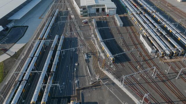 Aerial view of train maintenance facility in Auckland, New Zealand. Trains are parked on multiple tracks for servicing and repairs. The facility ensures the trains are safe and reliable.
