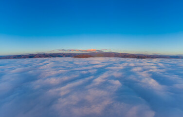 A stunning natural phenomenon known as a sea of ​​clouds or a cloud inversion. Landscape above the cloud layer