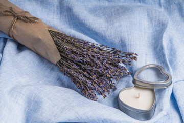 A bouquet of lavender next to a heart-shaped candle on a blue background.