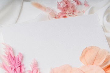 Minimalist card on soft white fabric with pink dried flowers.