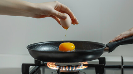 Woman hand holding black pan, egg dropping on pan,