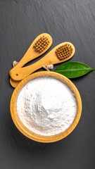 Powder in bowl, brushes, leaf on dark stone