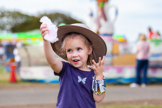 Happy little girl eating pink fairy floss as a treat at local Show event