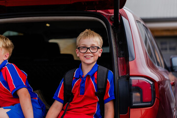 Portrait of happy Australian boy in public school uniform carrying backpack by car