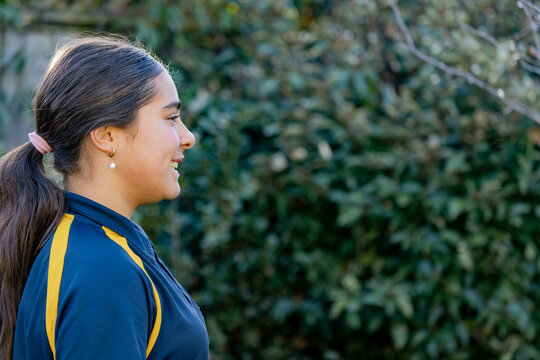 Side profile portrait of a pre teen girl smiling wearing a pearl earring