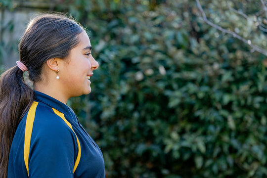 Side profile portrait of a pre teen girl smiling wearing a pearl earring