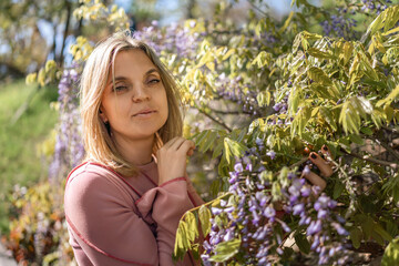 Blonde woman wisteria blossoms spring garden portrait