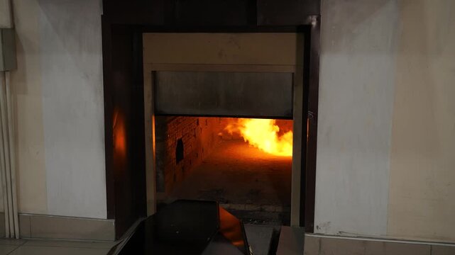 The crematorium stove opens with a burning flame inside