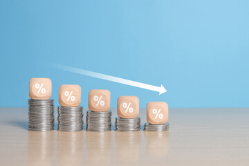 Coins stacking on wooden cube block with white down arrow and difference size percentage for financial recession crisis, interest rate decline, investment reduce, risk management concept