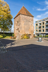 The medieval Kruittoren or Gunpowder Tower in Zutphen, Netherlands, a historic brick defensive structure with a tiled roof near modern buildings.