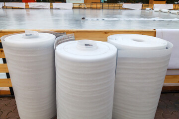 Three rolls of white polyethylene insulation film stand upright and are ready for use.