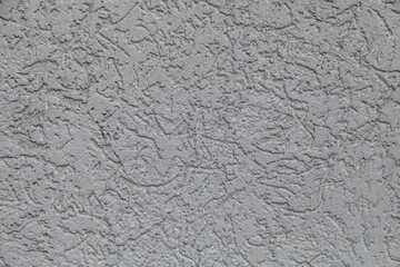 Grey wall with a textured surface. The wall is made of concrete and has a rough texture