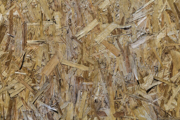 OSB boards made from brown wood chips sanded into a wooden background. Seamless surfaces of OSB wood board background.