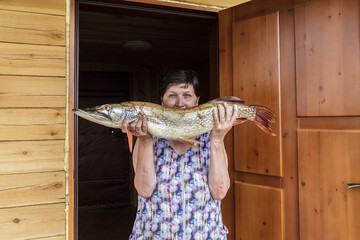 Woman is holding a large fish in her hands