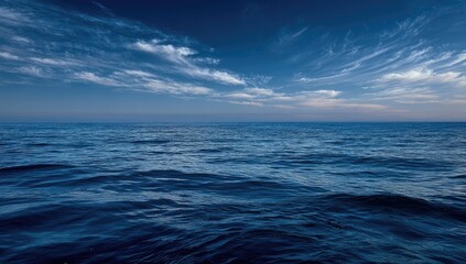 Fototapeta premium Deep blue ocean stretches to horizon under a vast sky with wispy clouds