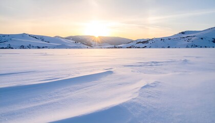 A snowy expanse beneath a pale sunrise, with distant hills and wind-swept snow
