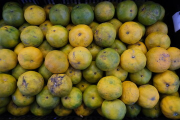 Organized display of several oranges, characterized by a mix of green and yellow hues that indicate...