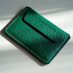 Emerald green leather card holder with white stitching on modern surface