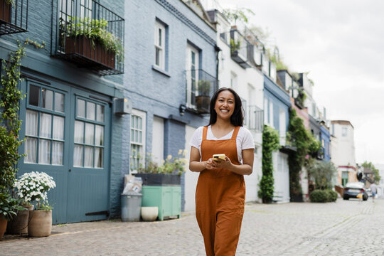 Smiling person walking outdoors using smartphone in colorful street
