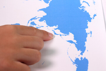 世界地図の日本を指さす子どもの手
