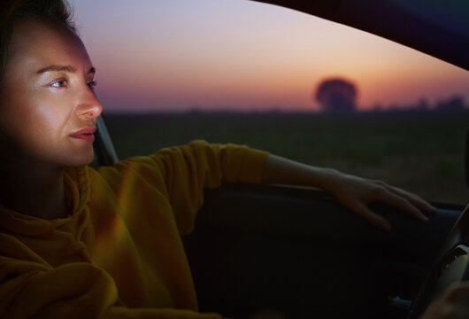 Driver in car at sunset on road trip with contemplative expression - Powered by Adobe