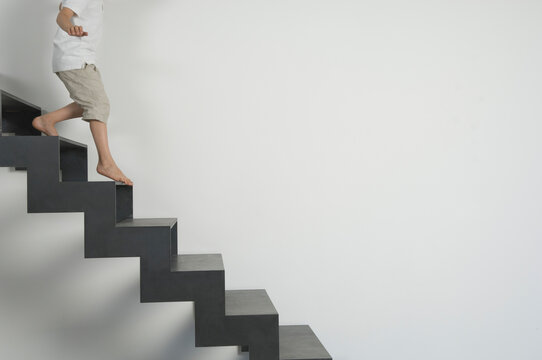 Child barefoot walking down modern staircase with minimalist background