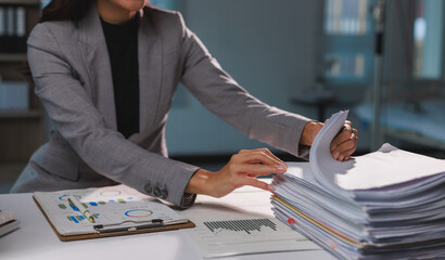Businesswoman organizing financial reports working late in office