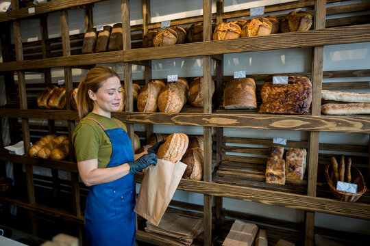 Shop assistant preparing bread in an artisan bakery indoors