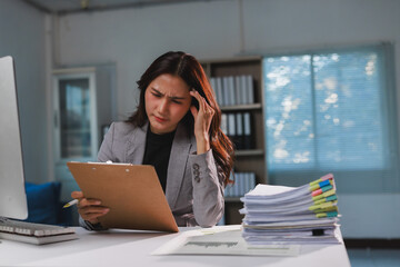 Businesswoman experiencing work stress and headache at office desk