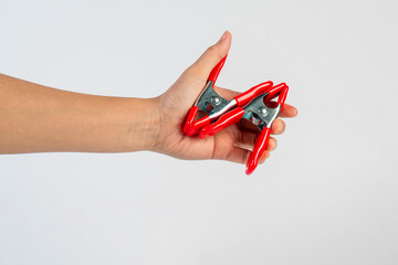 A studio shot of a red stainless spring clamp in hand isolated on a white background