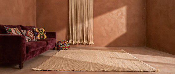Modern bohemian living room interior with a purple velvet sofa and woven rug against minimalist terracotta walls and macrame decor. Bohemian Home Decor.